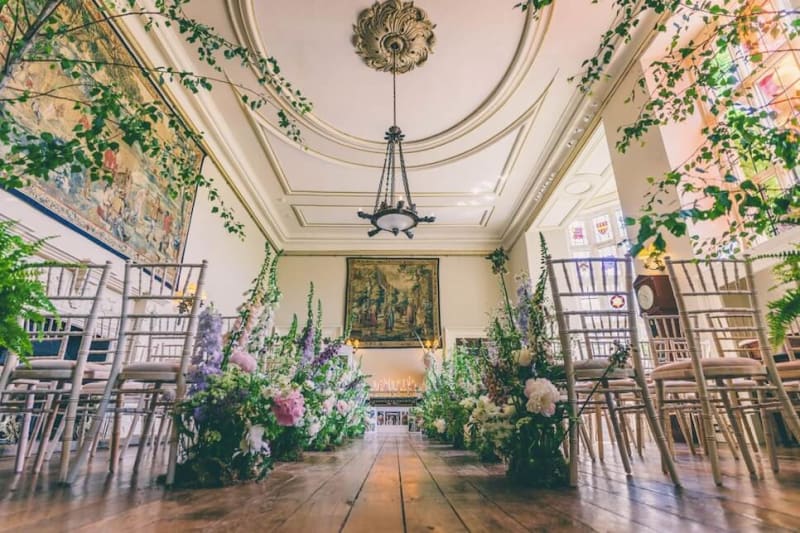 A low angle shot of an aisle set up inside and decorated with flowers for a wedding ceremony. 