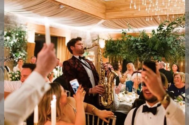 Man in tuxedo playing the saxophone at a wedding reception.