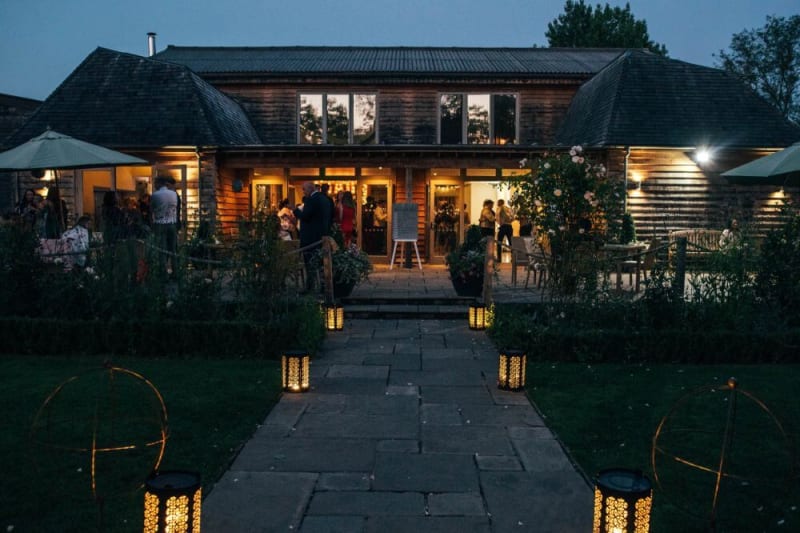 A wooden barn that also looks modern is filled with people.