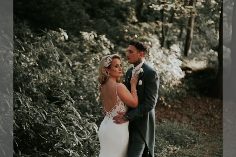 Bride and groom posing for a photo in the woods.