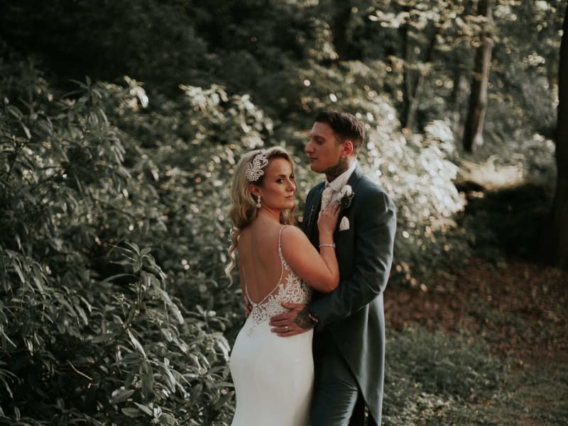 Bride and groom posing for a photo in the woods.