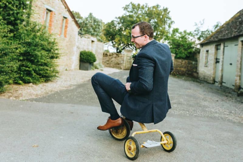 Man in suit rides a yellow tricicle.