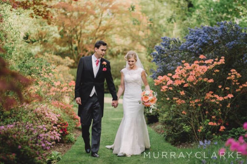 Bride and Groom hold hands and walk past the flowers.