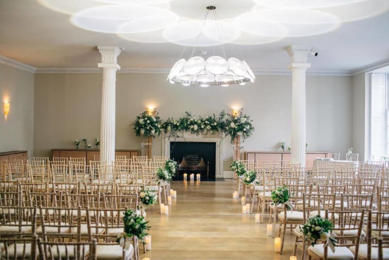 Chairs and aisle set up and decorated with flowers inside for a wedding ceremony. 