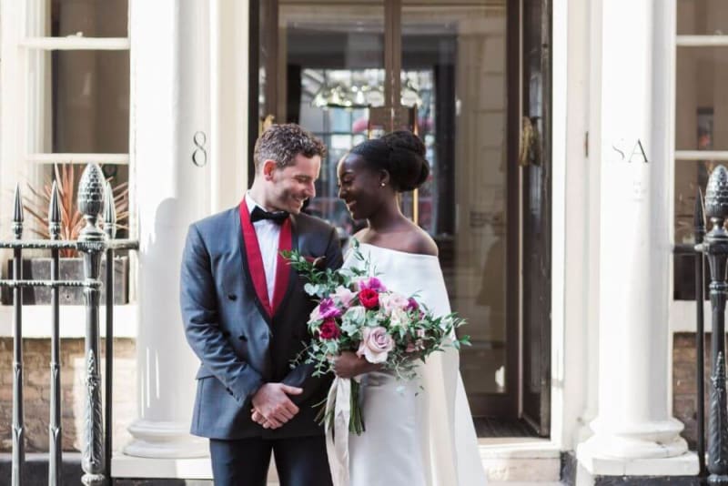 Bride and groom outside the venue smiling at each other. 