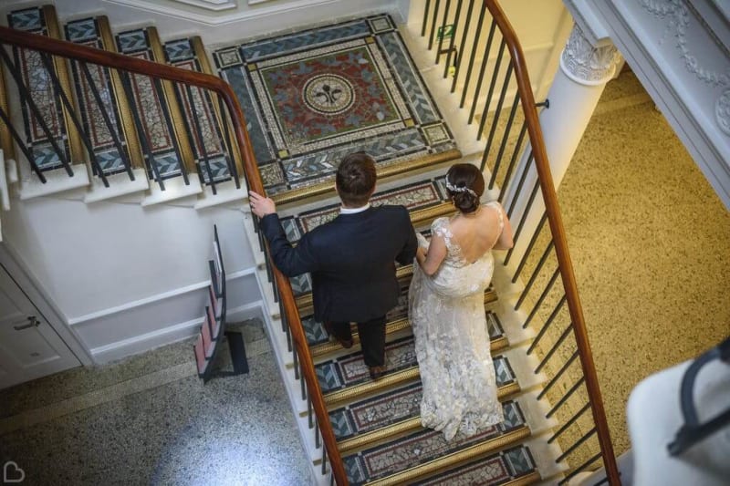 Bride and groom walking up a staircase.