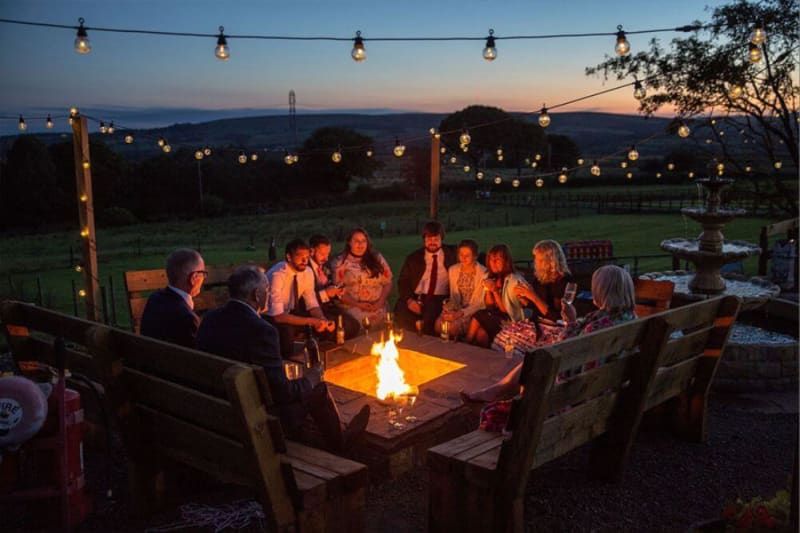Group of people sitting around a campfire in the evening.