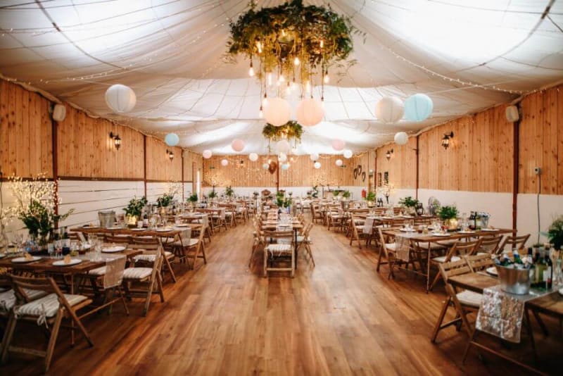 Inside of a wedding venue with tables and decorations set up for a wedding.