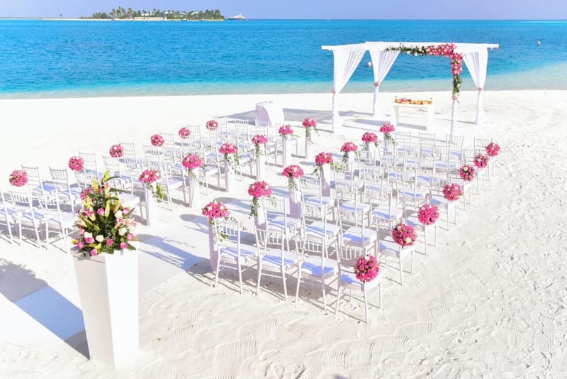 Pink flowers wedding chair decorations on white chairs for stunning beach wedding outdoors