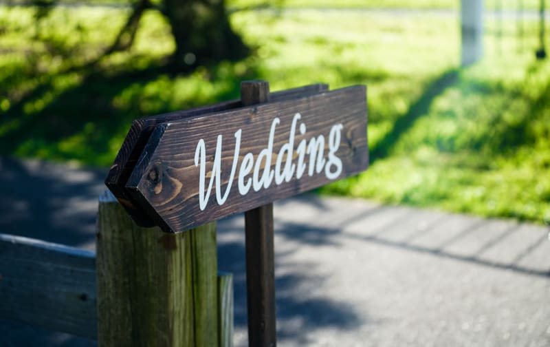 Wooden wedding sign outdoors showing wedding guests where wedding is