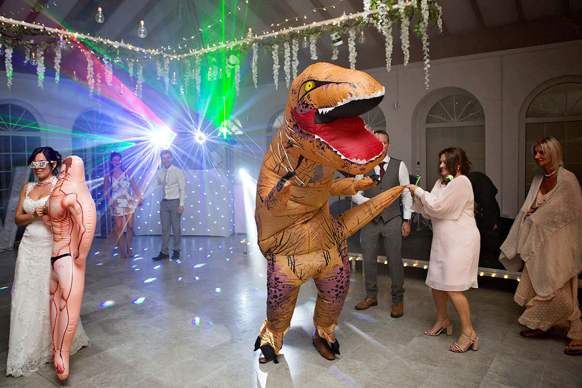 guest in t-rex costume dances at wedding