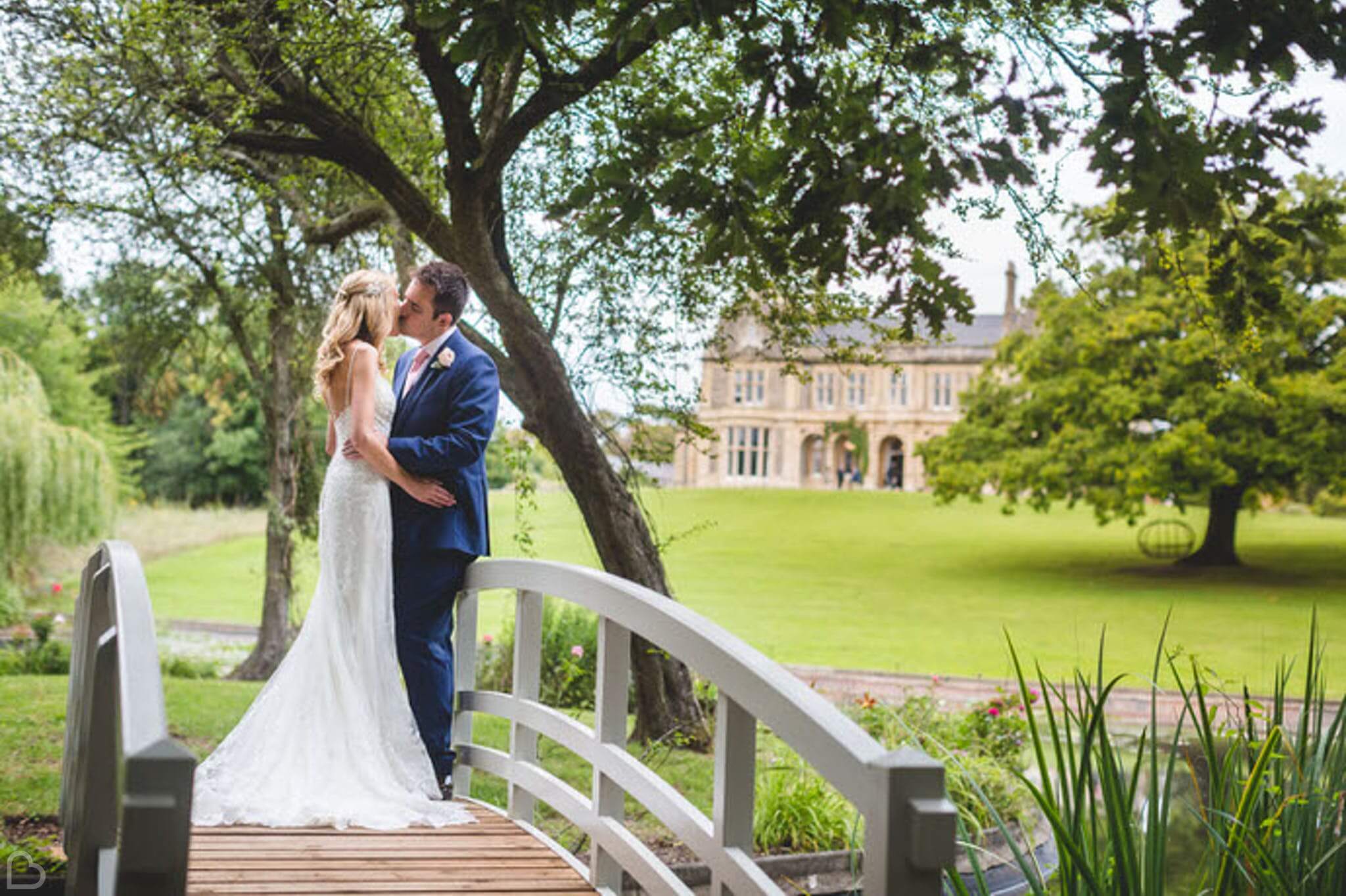 newlyweds kissing on a small bridge, at clevedon hall, a wedding venue in somerset.