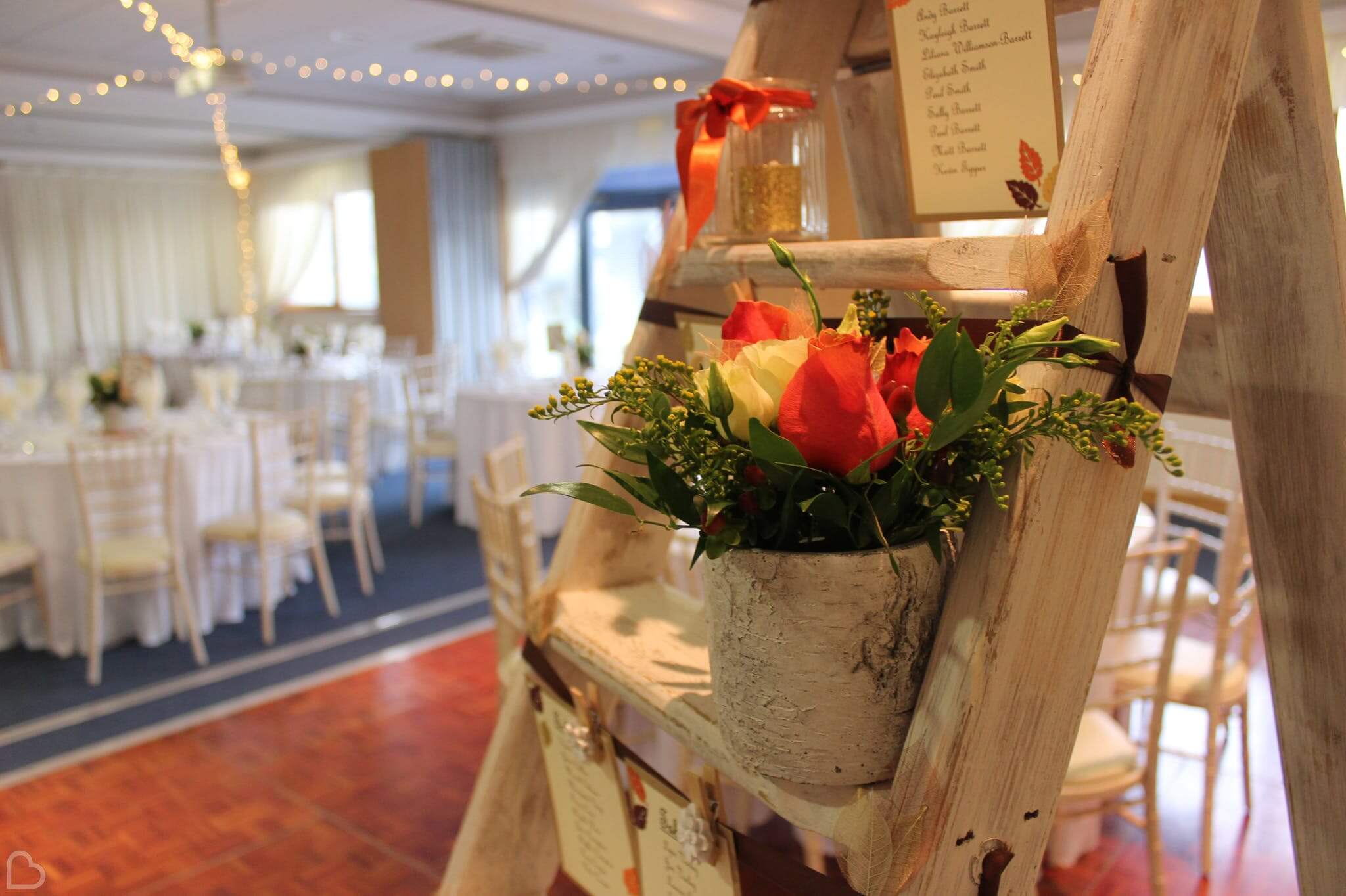 A flower pot is set up next to table seating charts at South Green Park Weddings, a beautiful wedding venue in Norfolk.