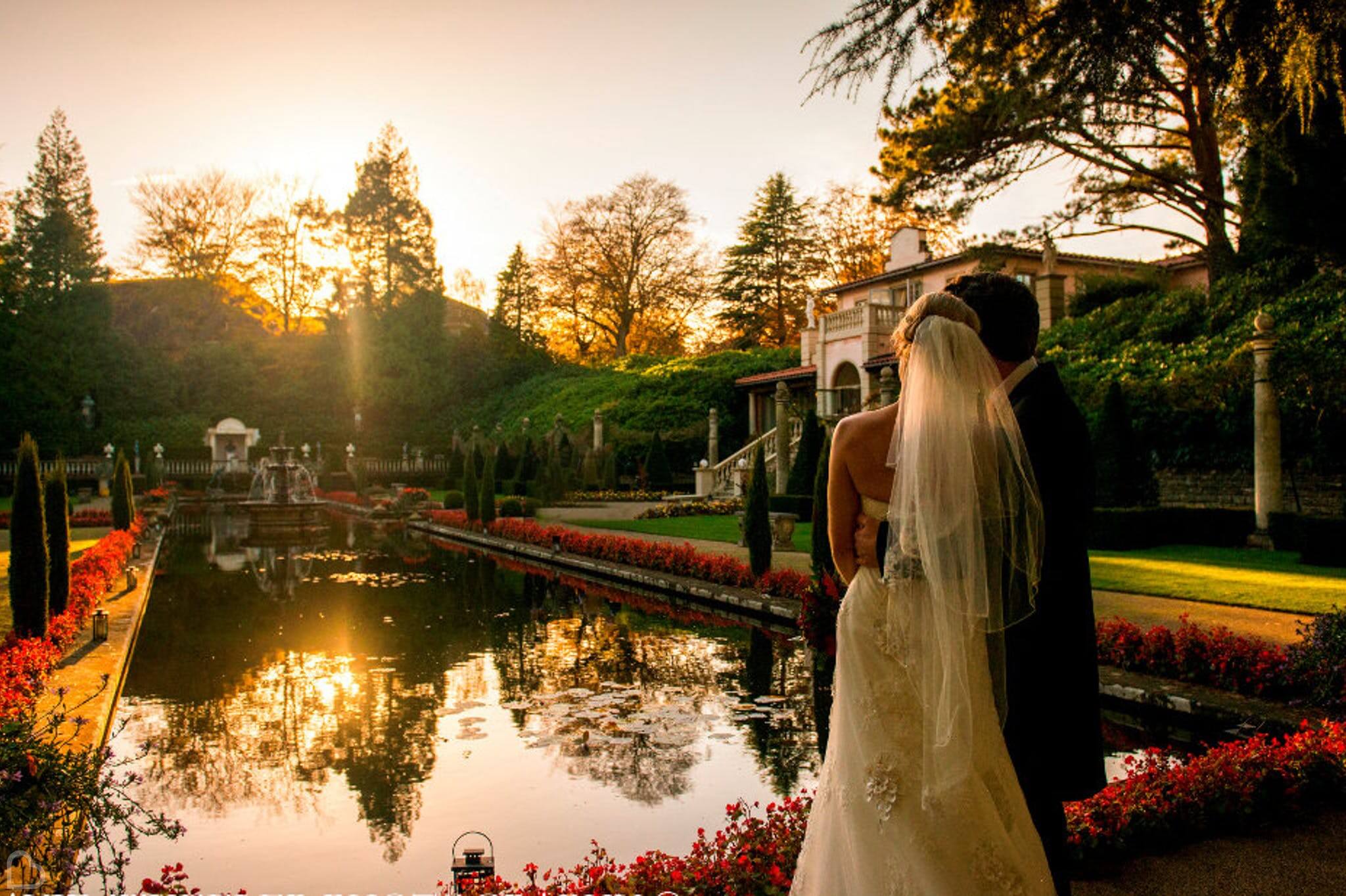 newlyweds embrace and watch the sunset over a lake at the italian villa at compton acres, a wedding venue in dorset.