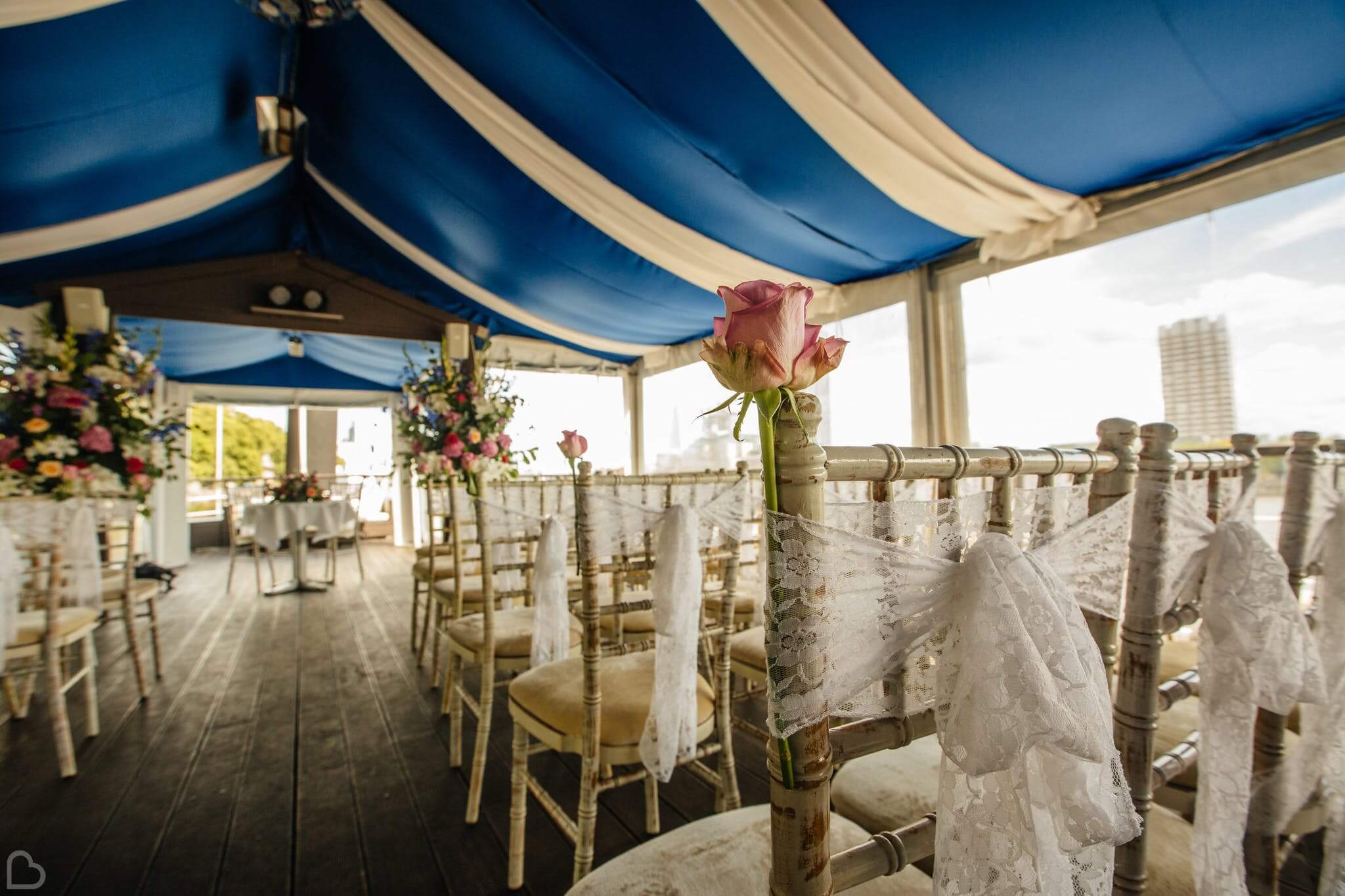 the yatch london chairs set up for a wedding ceremony with a rose and lace on each chair.