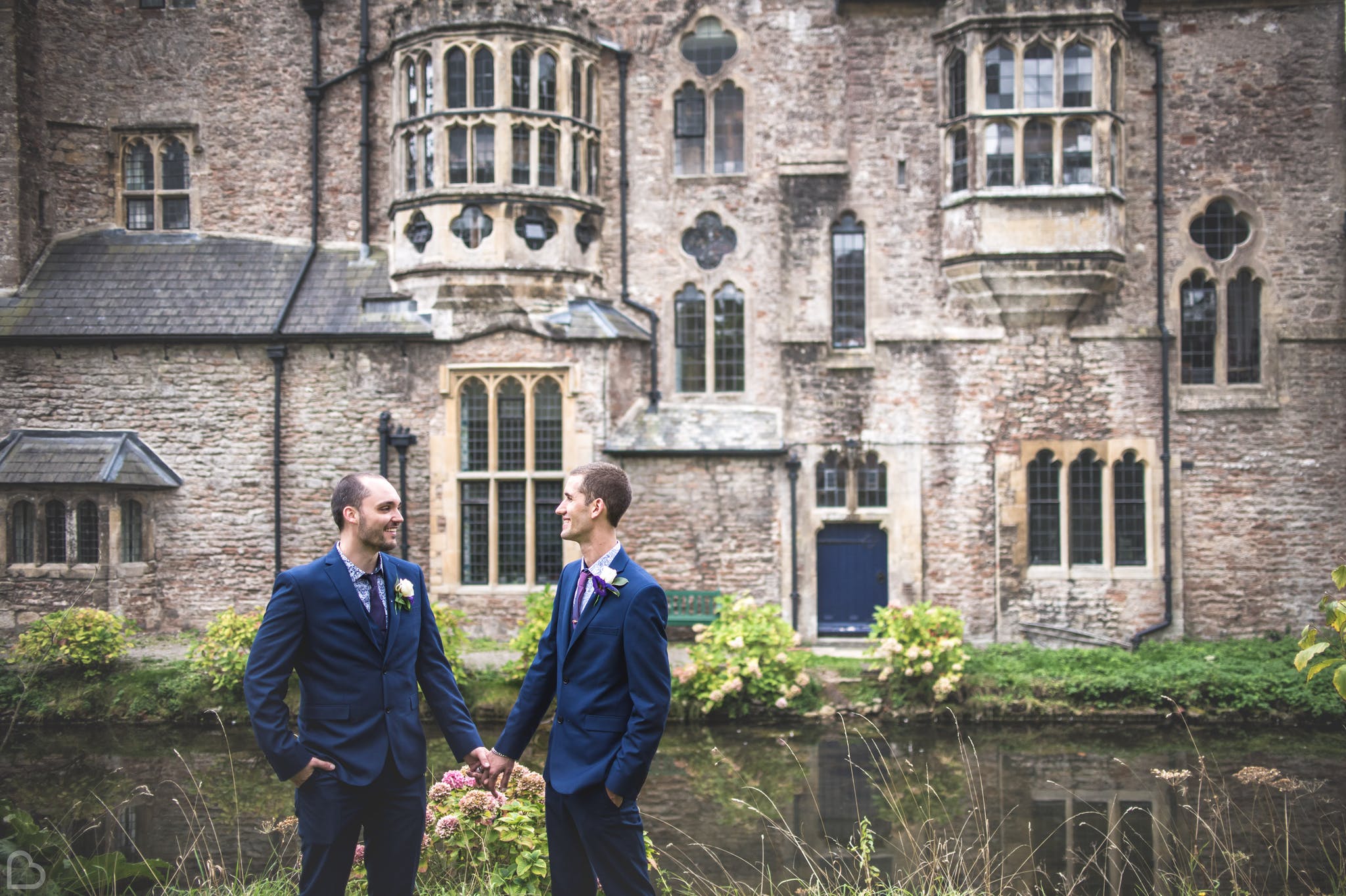 Newlyweds hold hands in front of Bishop's Palace in Somerset.