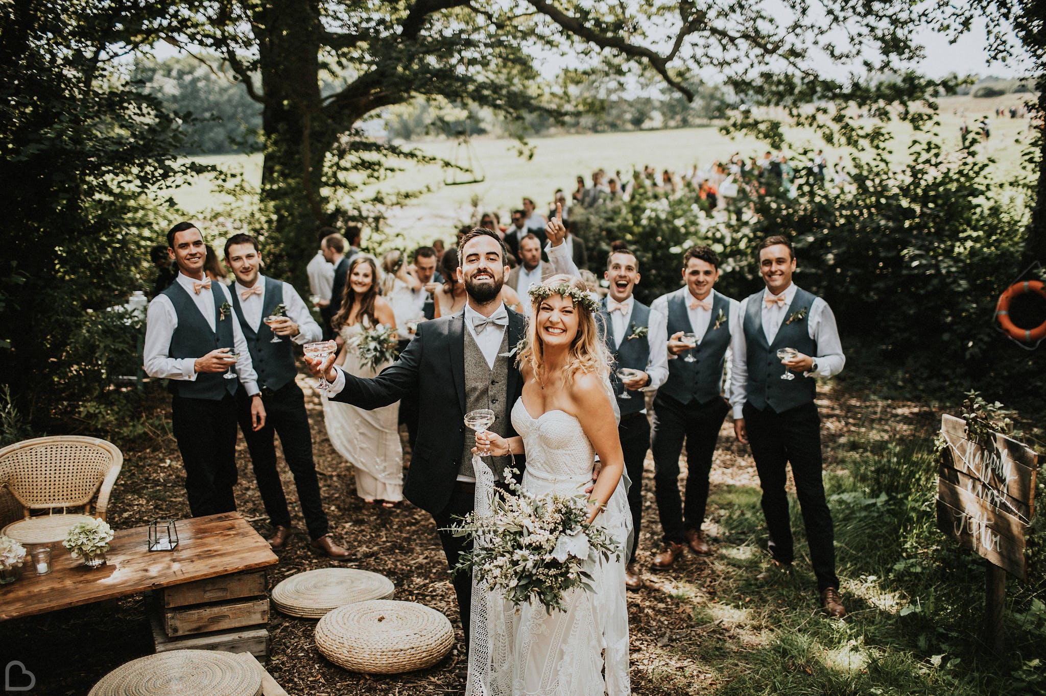 Bride with flower crown and groom celebrating their wedding outdoors with loved ones