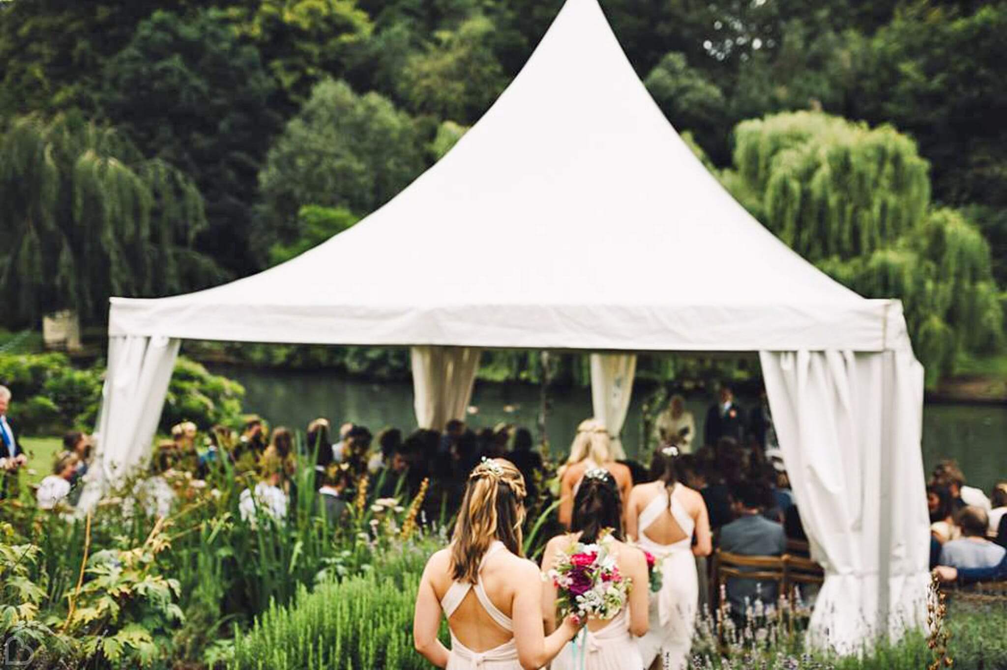 Busbridge Lakes in Surrey, bridemaids approach wedding ceremony by the lake.