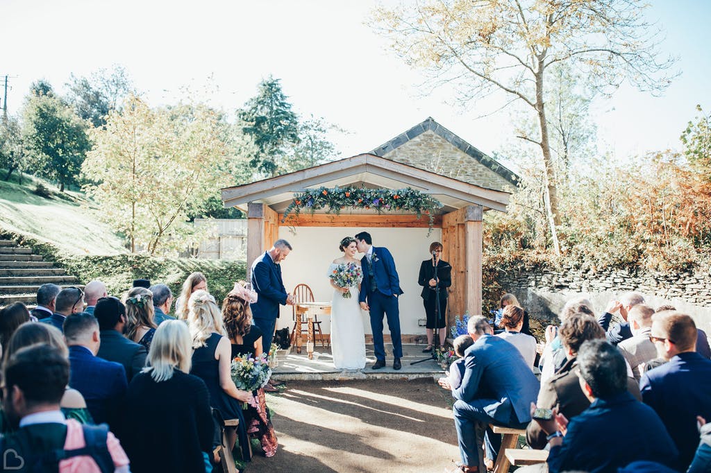 Groom tells bride a secret as they prepare as their outdoors wedding ceremony ends. 