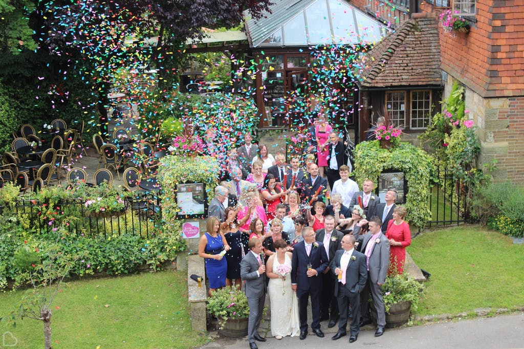 Wedding guests throw confetti outside The Barn. A cheap wedding venue in Kent.