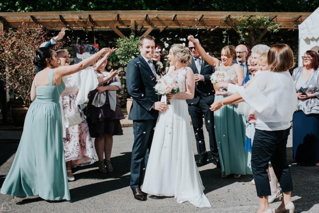 Guests throw rose petals at newlyweds. 