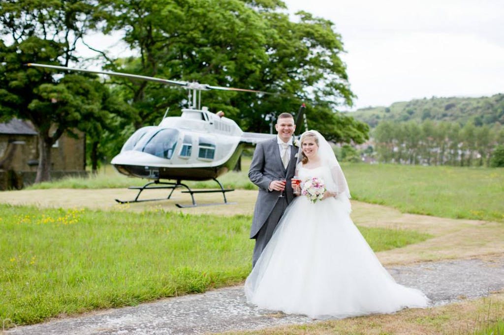 Newlyweds pose in front of helicopter at The Thatched Barn