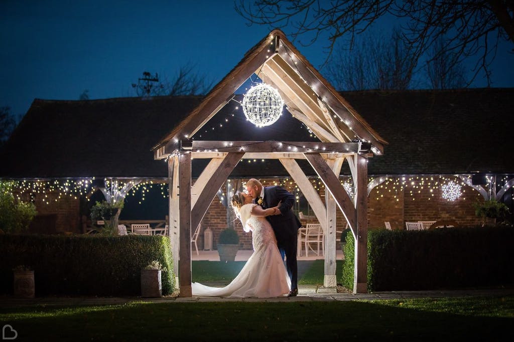 Newlyweds kiss surrounded by fairy lights in the garden.