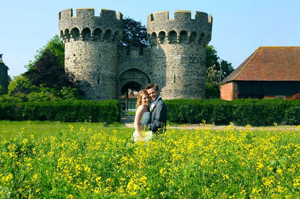 Newlyweds pose in front of castle tower at the cooling castle barn.