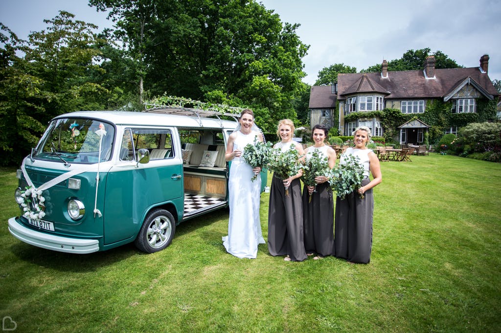 Bride and her bridesmaids pose in front of venue.