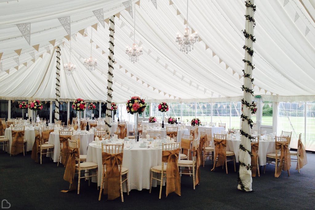 Marquee set up for wedding lunch with greenery and autumn tones. 