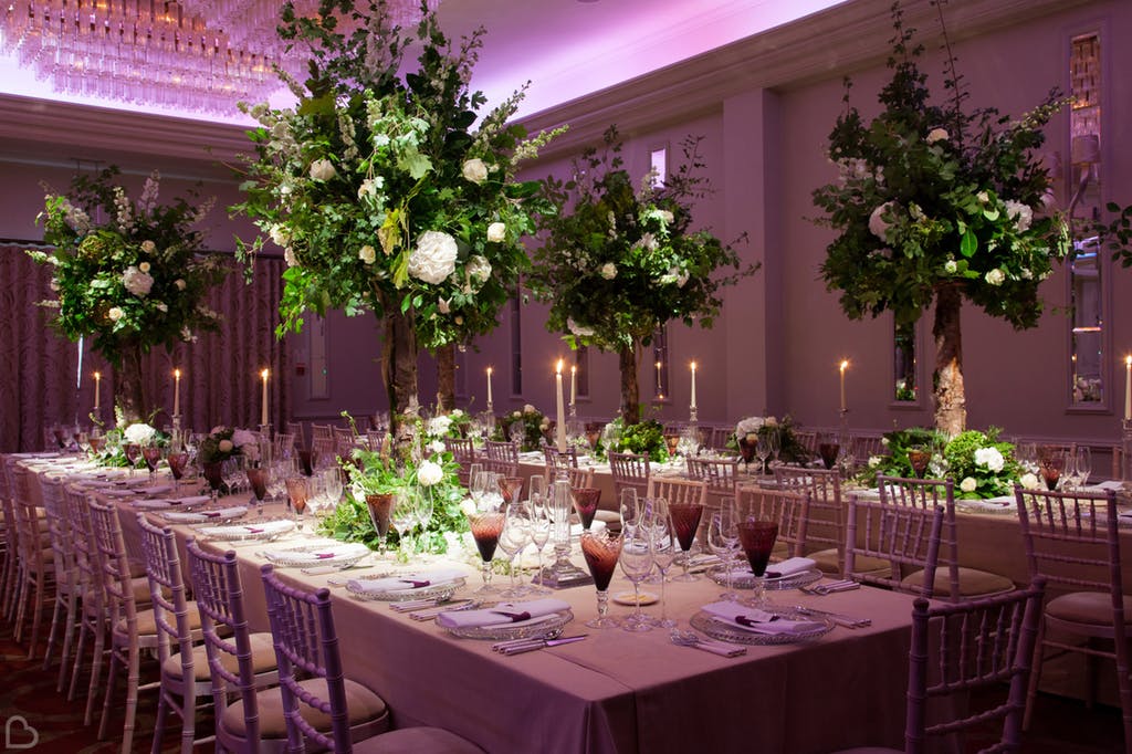 Tables set up with big greenery pieces and dim lighting.