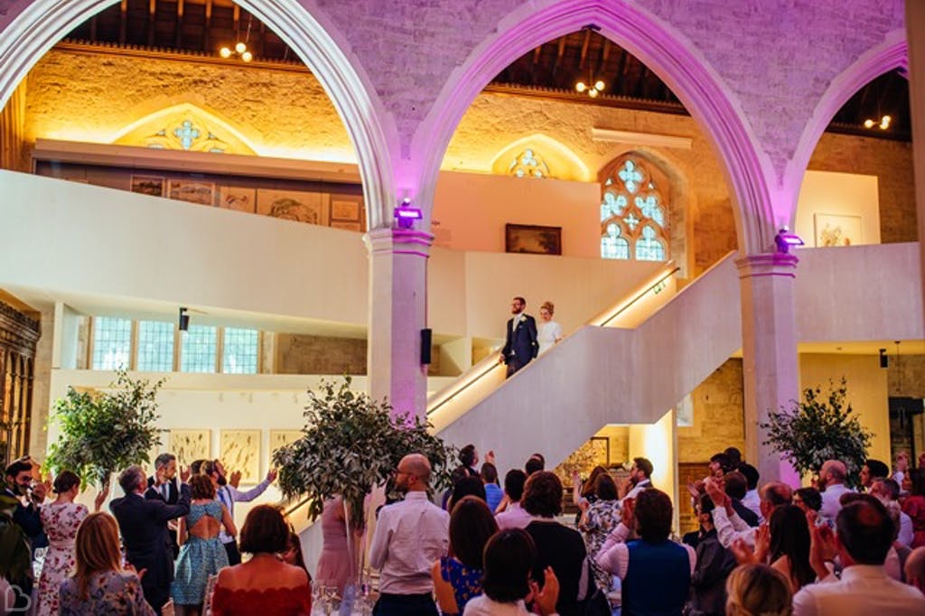 newlyweds coming down the stairs as guests cheer at the garden museum.