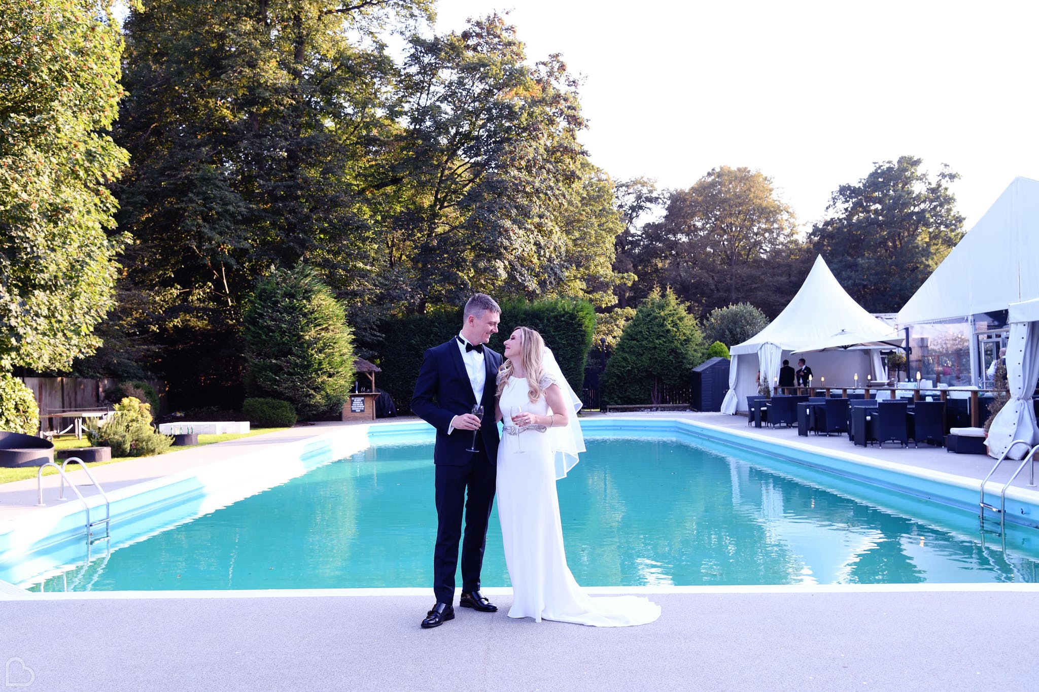 newlyweds pose in front of the pool and the kings oak hotel