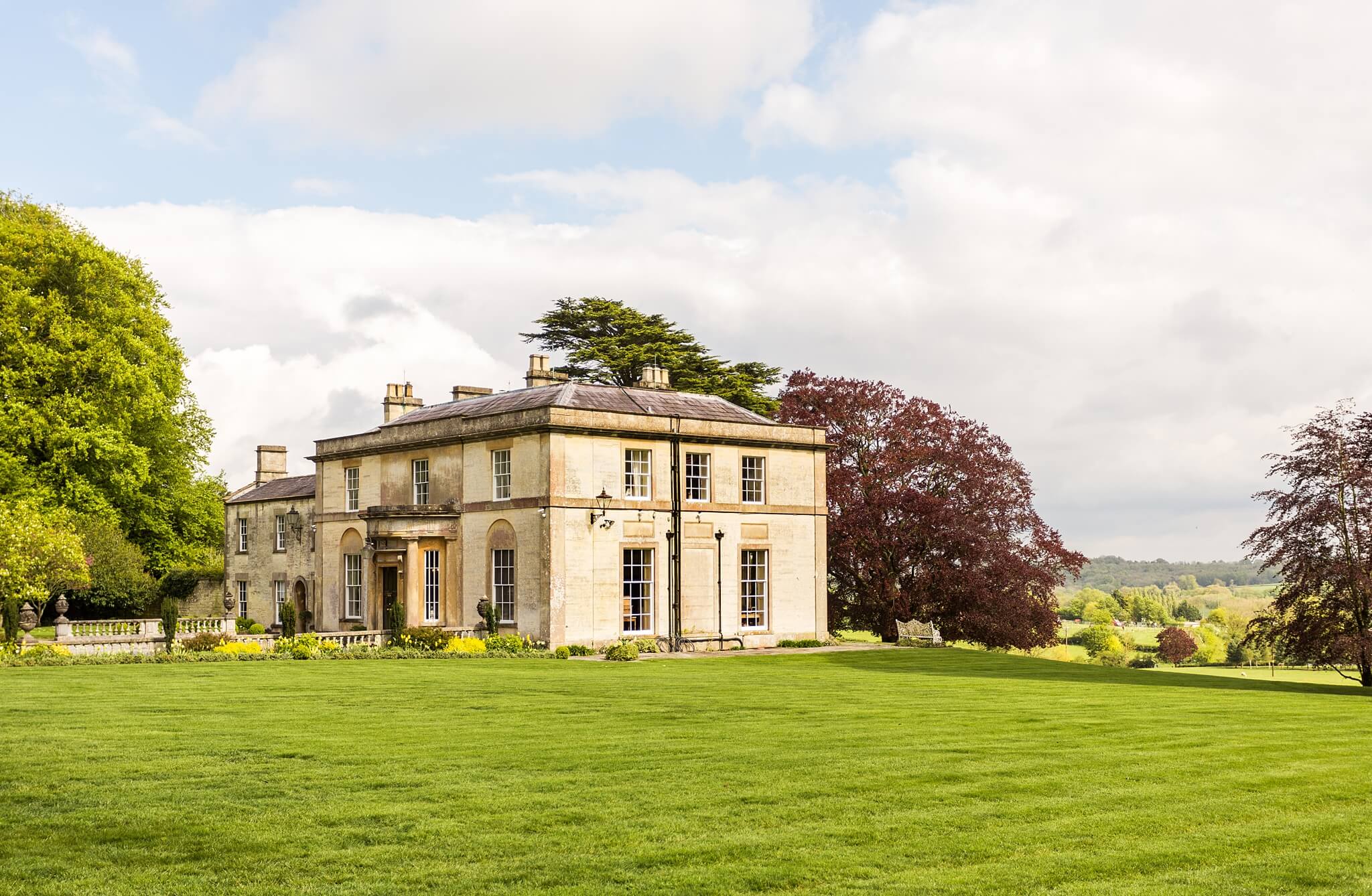 Stately home surrounded by green grass and trees.