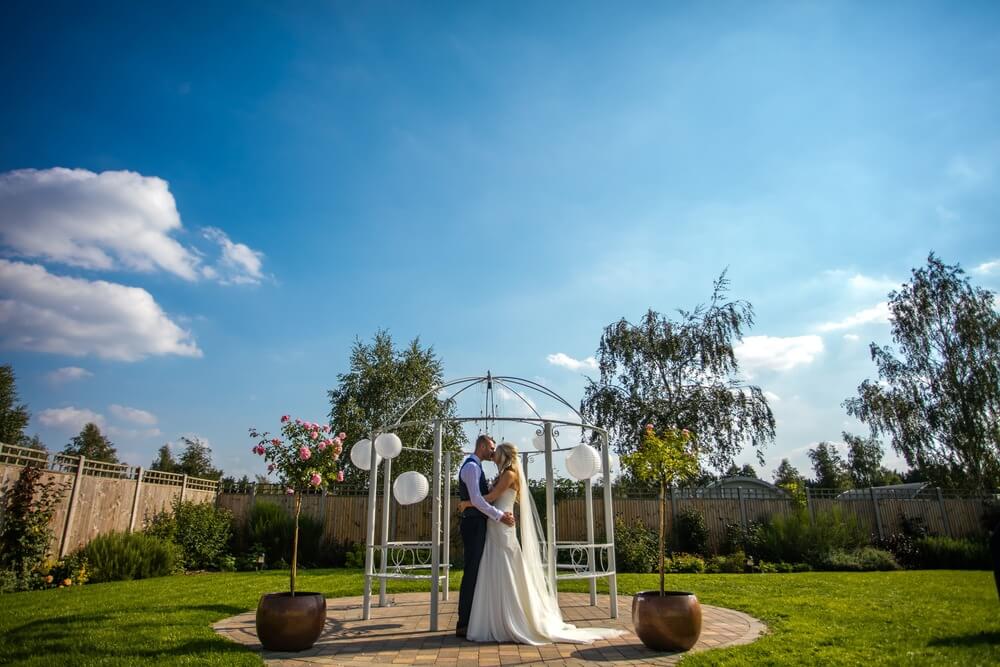 In the daylight, a couple kisses in the gazebo.