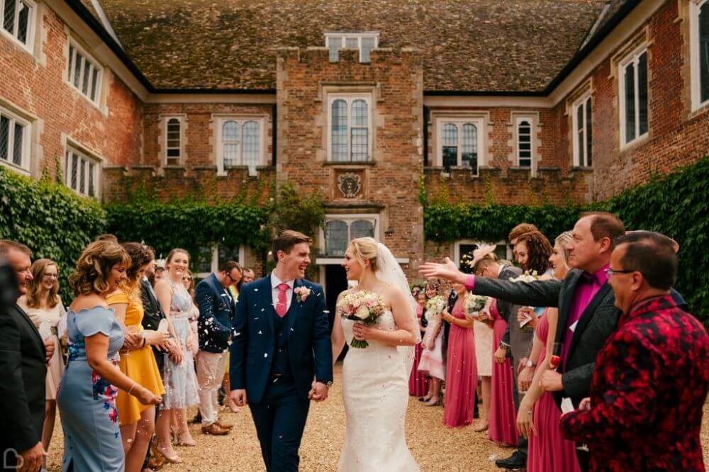 The couple leaves holding hands while people around them cheer.