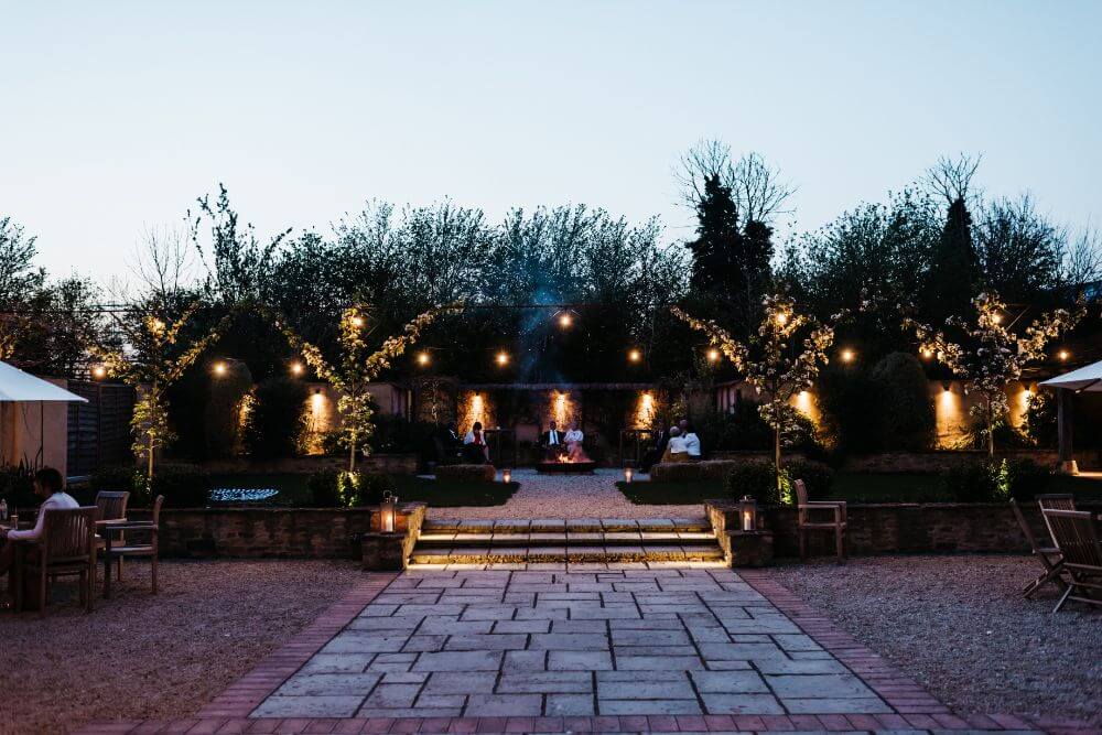 In the evening, people are siting in piles of hay and the trees surrounding them are covered in lights.