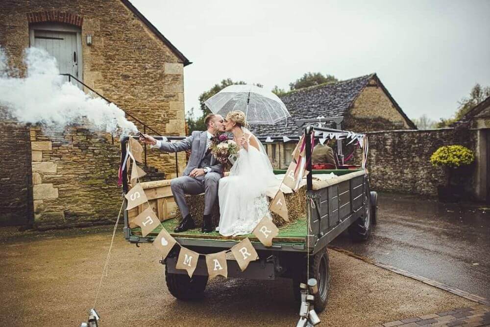 A couple rides the back of a carriage while kissing.