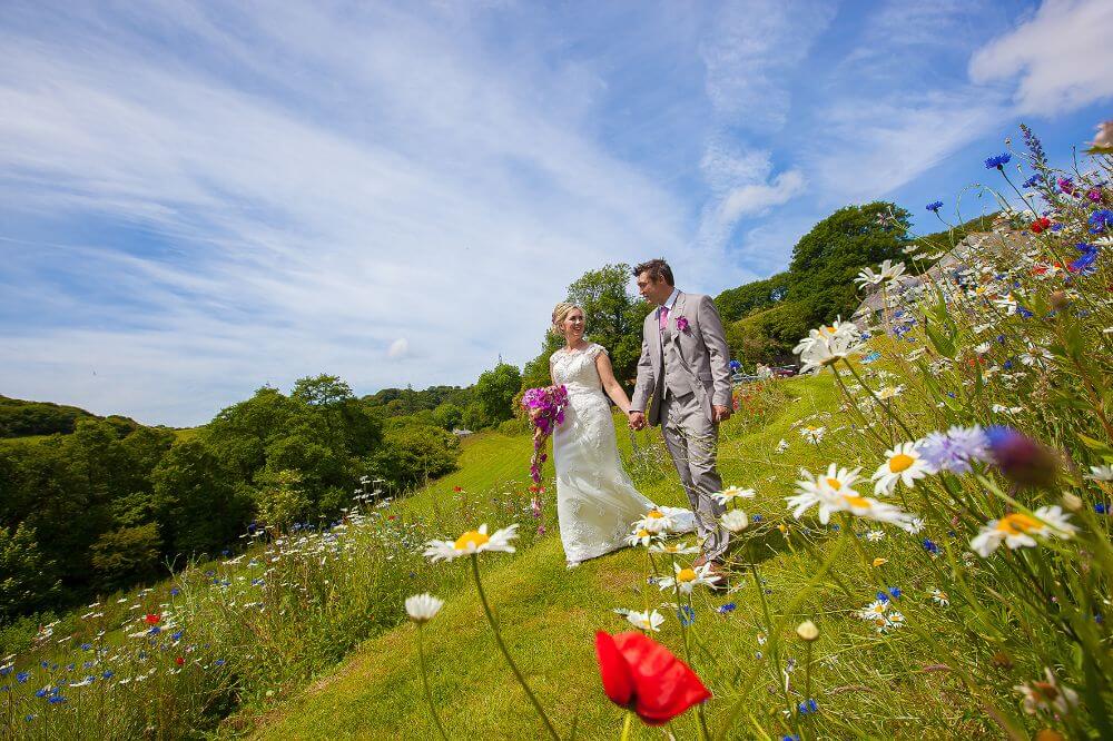 Bride and Groom take a stroll down a hill with flowers.