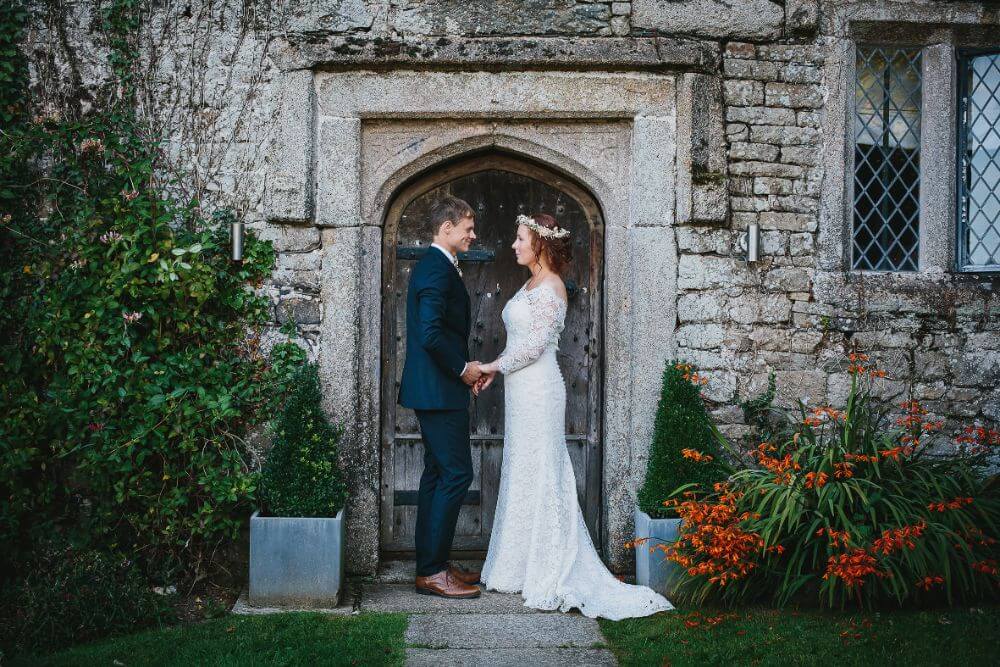 Bride and Groom look lovingly at each other in front of an ancient door.