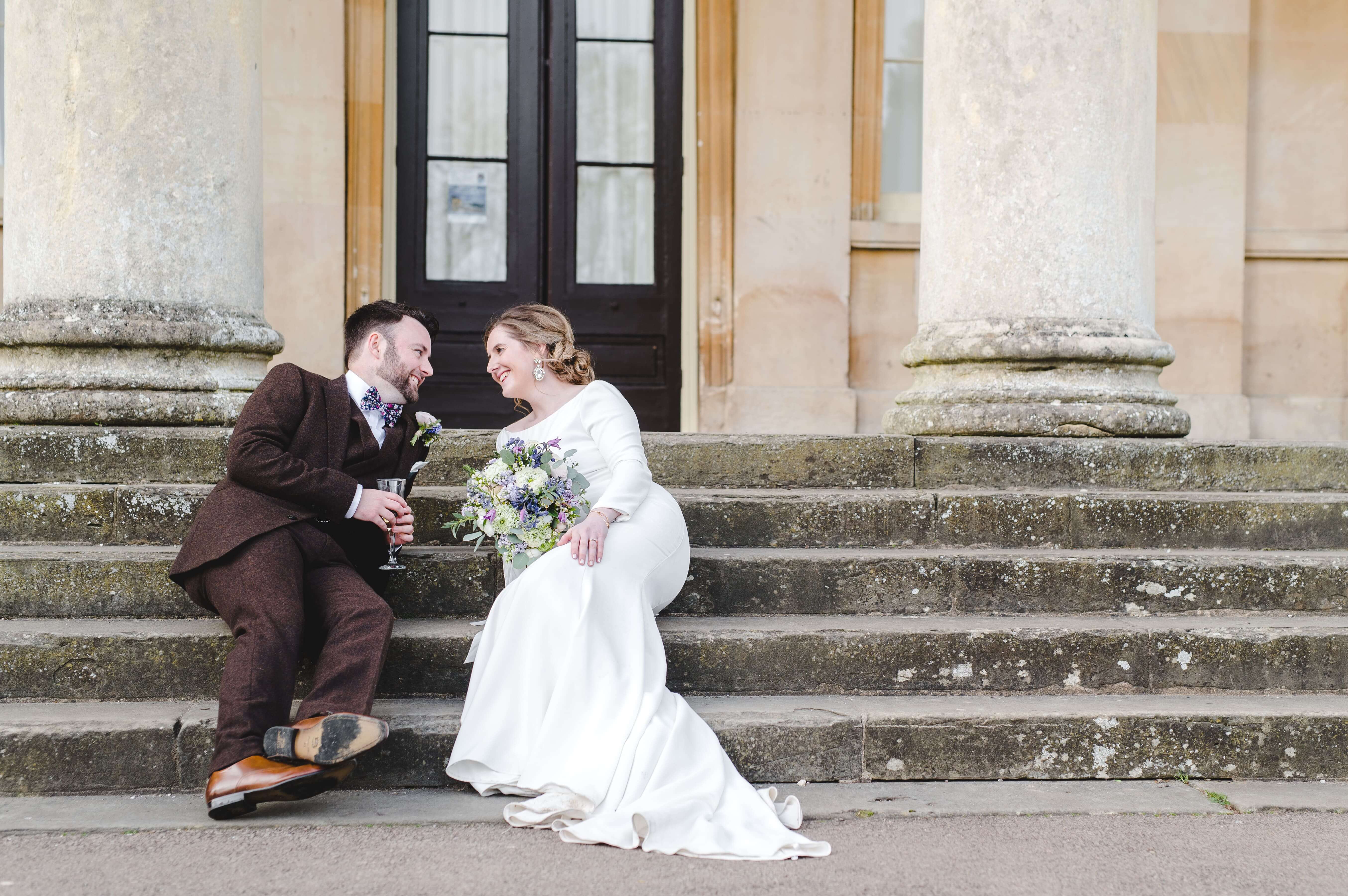 Adam and Faye Hughes sitting on steps in their wedding clothes