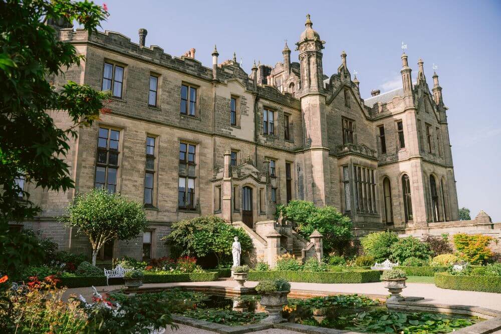 Photograph of the outside of a castle and a pond. 