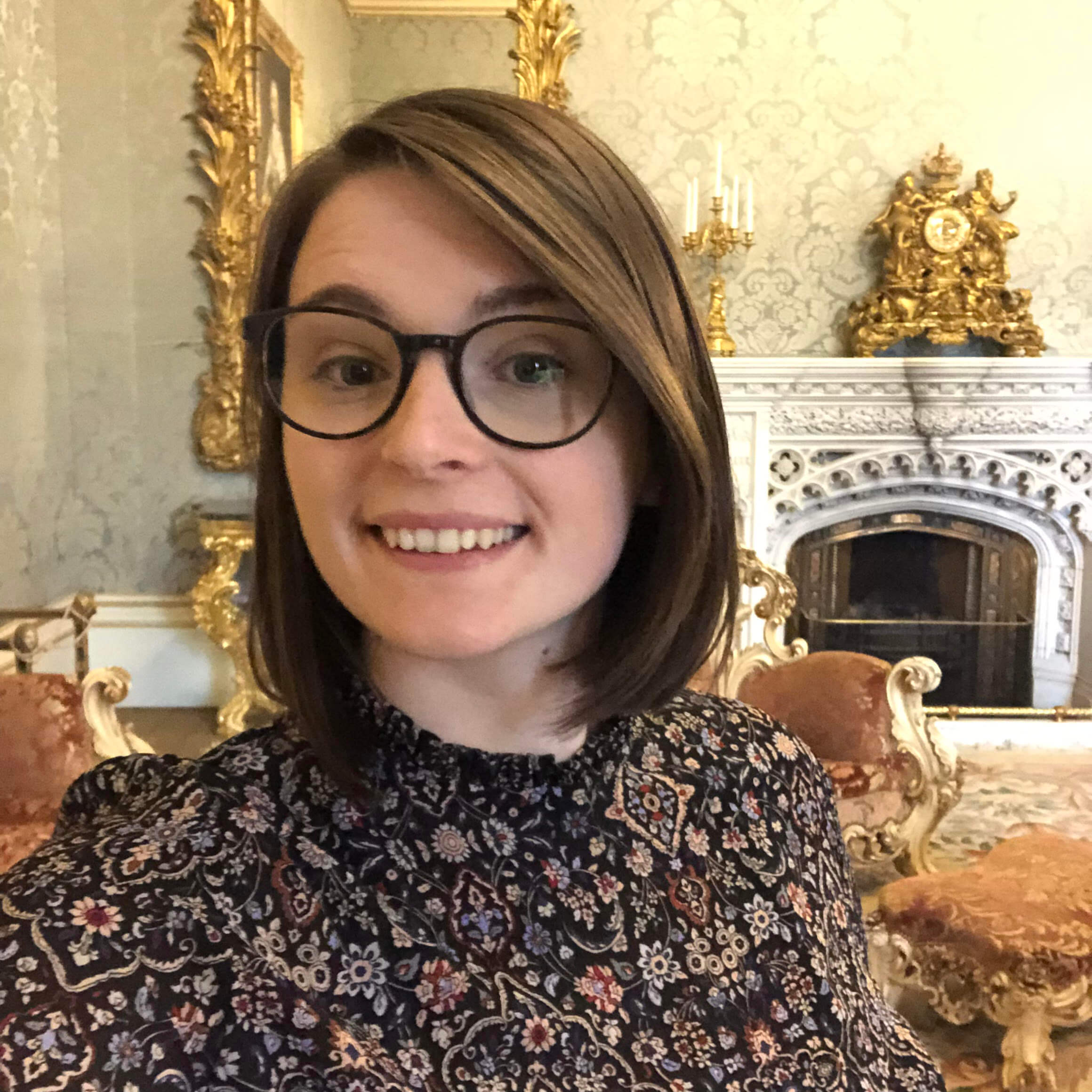 Brunette woman with glasses smiling into camera. 