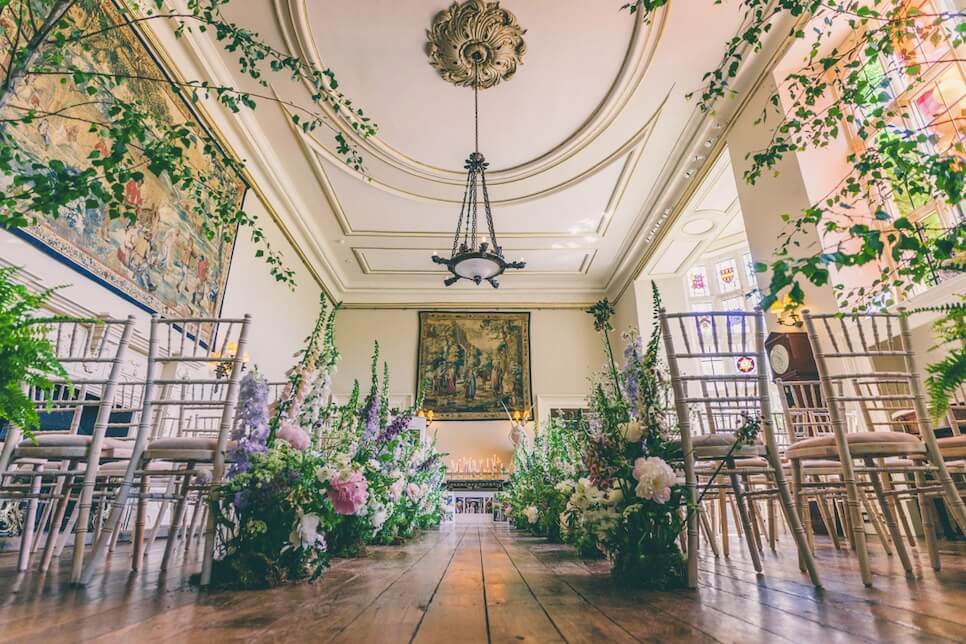 A low angle shot of an aisle set up inside and decorated with flowers for a wedding ceremony. 