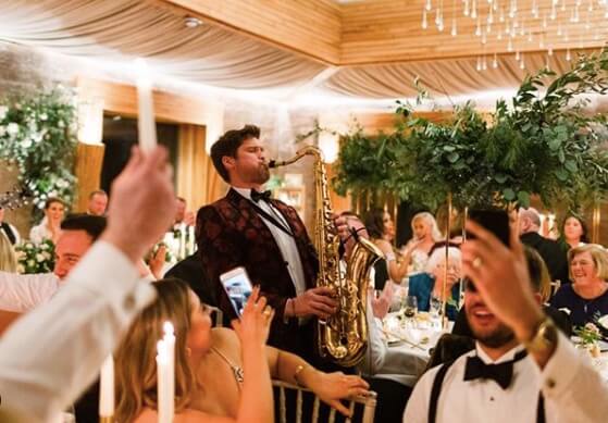 Man in tuxedo playing the saxophone at a wedding reception.