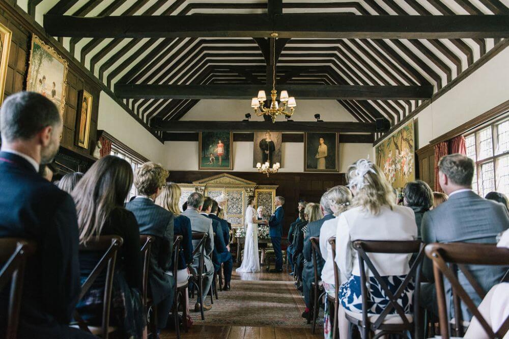 A ceremony inside with people looking on as bride and groom say their vows.