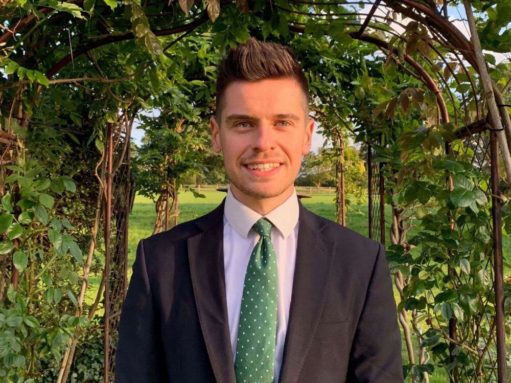 Man in suit smiling into camera.
