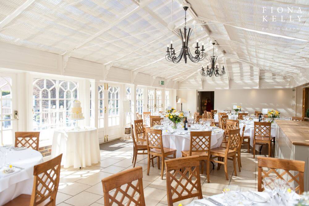 several tables inside a white tent are set for a wedding.