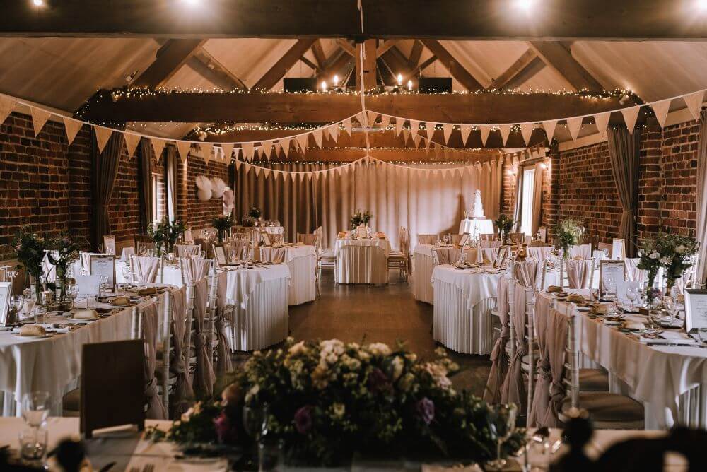 Inside the barn where the tables are set with a white cloth and flowers.