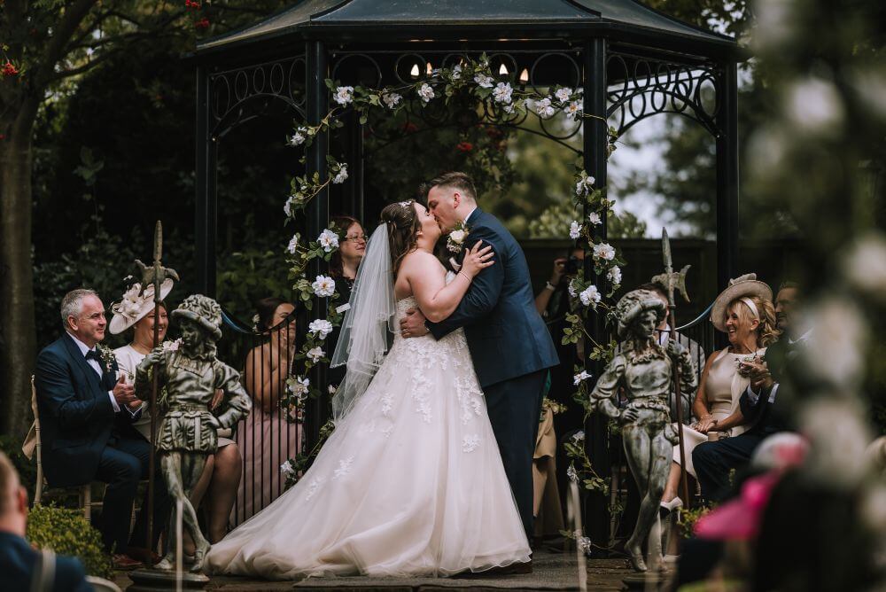 The bride and groom kiss under the gazebo.
